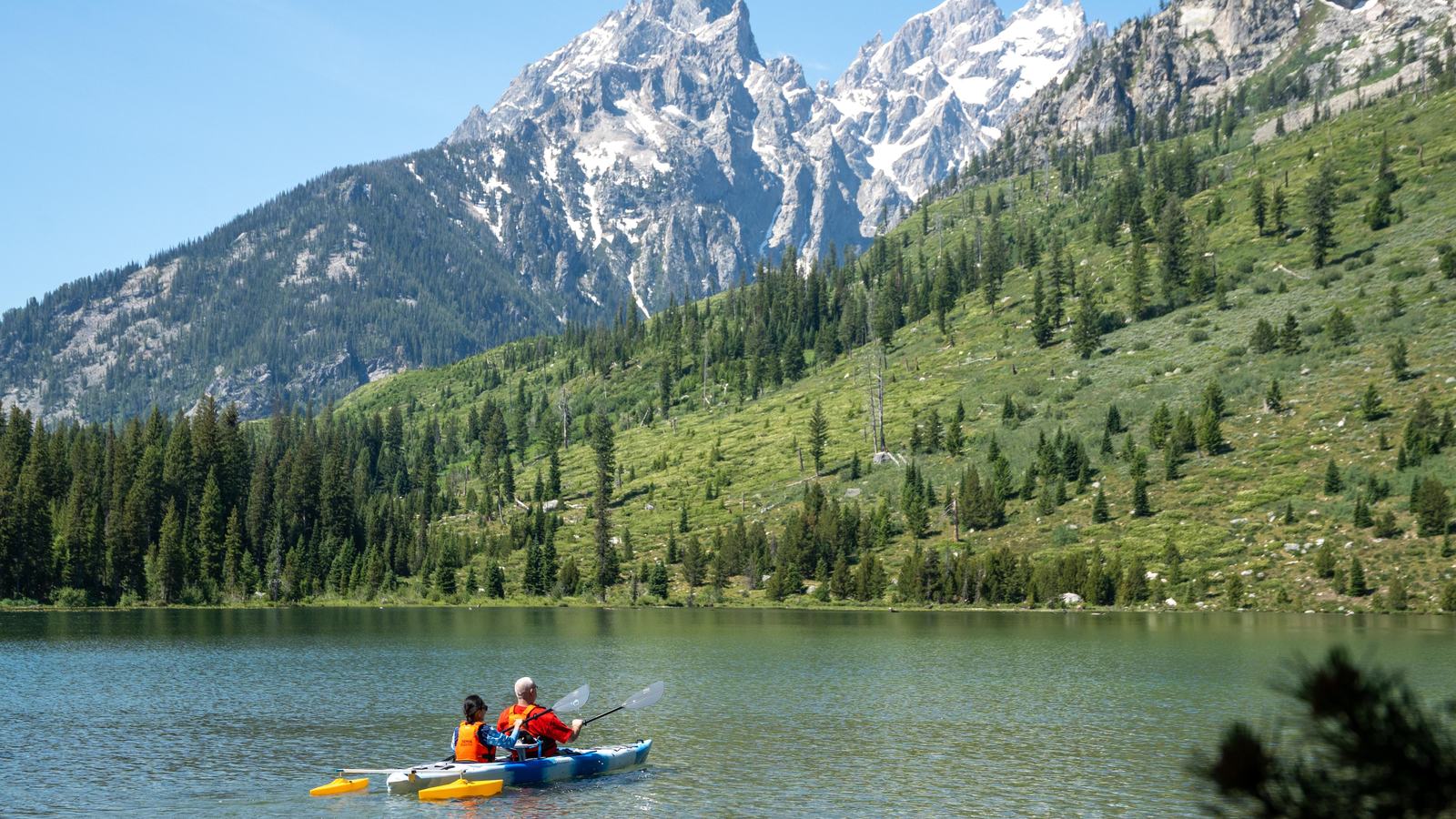 National Park Service, two kayakers on a lake beneath the Teton mountains
